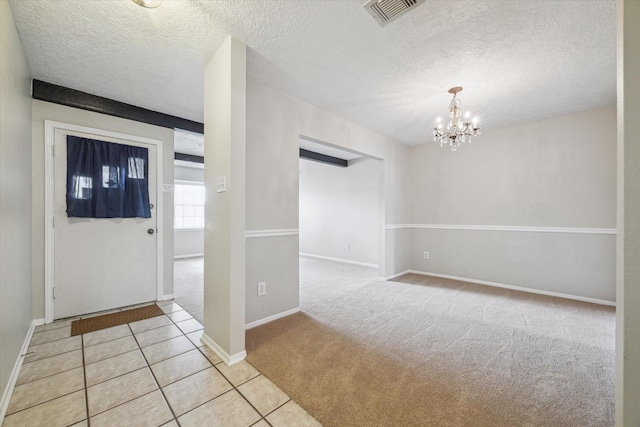 entrance foyer featuring light carpet, a textured ceiling, and a chandelier