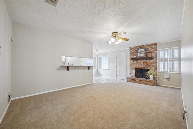 unfurnished living room featuring ceiling fan, light carpet, a textured ceiling, and a fireplace