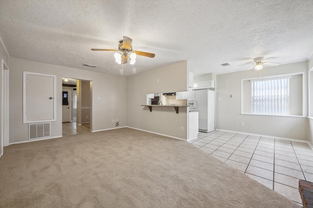 unfurnished living room featuring light colored carpet, a textured ceiling, and ceiling fan