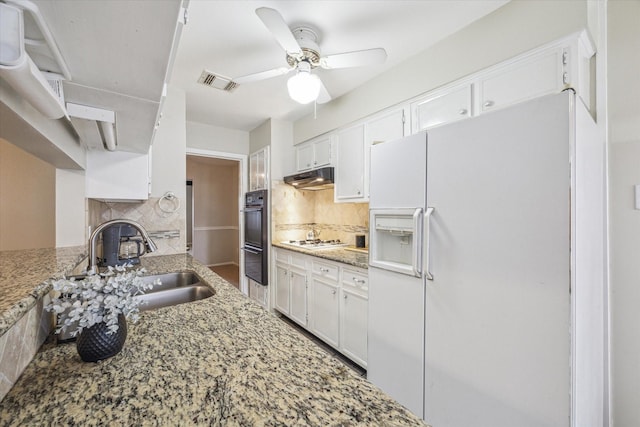 kitchen featuring sink, white appliances, white cabinetry, light stone countertops, and decorative backsplash