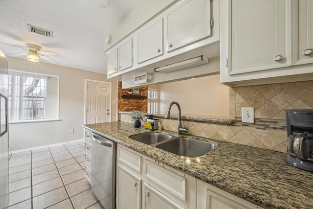 kitchen featuring sink, light tile patterned floors, dark stone countertops, white cabinets, and stainless steel dishwasher