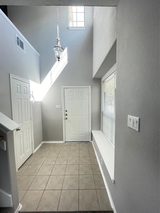 entrance foyer featuring a high ceiling, light tile patterned flooring, and plenty of natural light