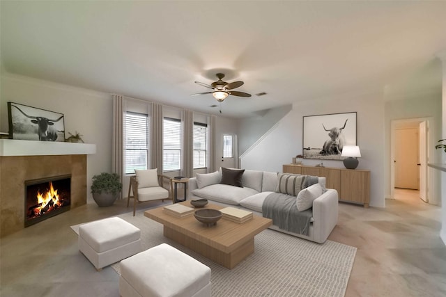 living room featuring a tile fireplace and ceiling fan