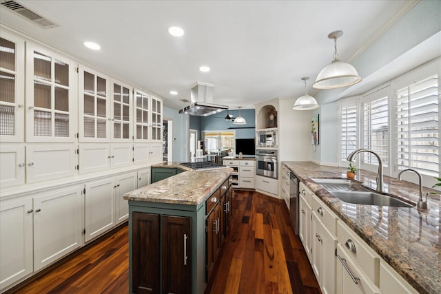 kitchen featuring sink, hanging light fixtures, appliances with stainless steel finishes, a kitchen island, and light stone countertops