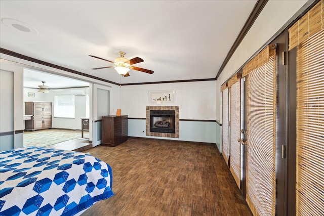 bedroom featuring ceiling fan, ornamental molding, dark hardwood / wood-style floors, and a tiled fireplace