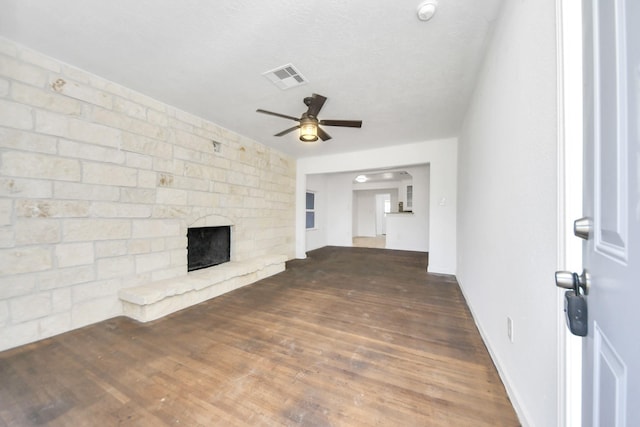 unfurnished living room with ceiling fan, dark wood-type flooring, a textured ceiling, and a fireplace