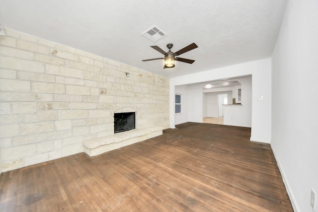 unfurnished living room featuring a textured ceiling, a fireplace, dark hardwood / wood-style floors, and ceiling fan