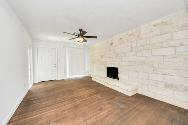 unfurnished living room featuring ceiling fan, a stone fireplace, and dark hardwood / wood-style flooring