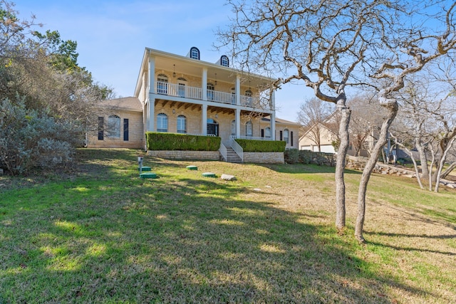 back of property featuring a balcony, a yard, and covered porch