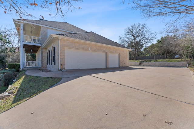 view of side of home featuring a garage and a balcony