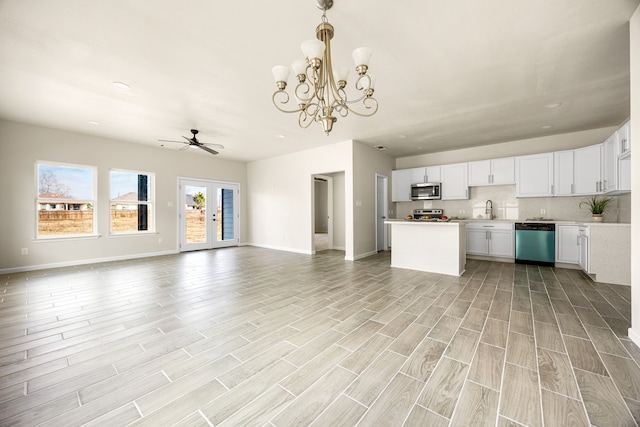 kitchen featuring french doors, white cabinetry, tasteful backsplash, appliances with stainless steel finishes, and pendant lighting