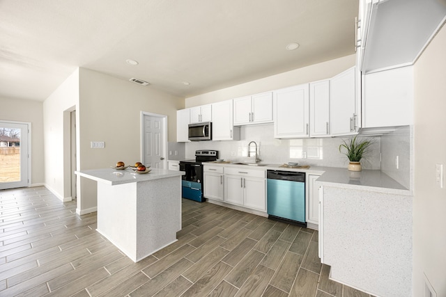 kitchen featuring sink, a center island, appliances with stainless steel finishes, decorative backsplash, and white cabinets