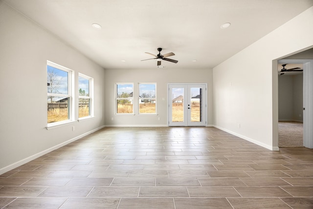 unfurnished living room featuring a healthy amount of sunlight, light hardwood / wood-style flooring, ceiling fan, and french doors