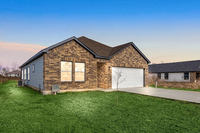 view of front of house with cooling unit, a garage, and a lawn