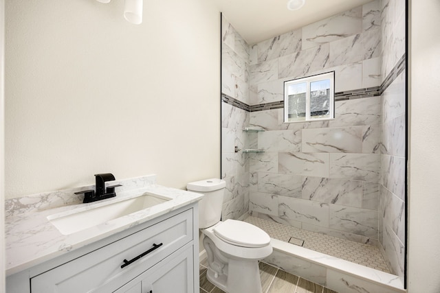 bathroom with vanity, toilet, and a tile shower