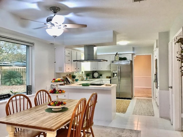 kitchen featuring stainless steel refrigerator with ice dispenser, sink, white cabinetry, island range hood, and kitchen peninsula