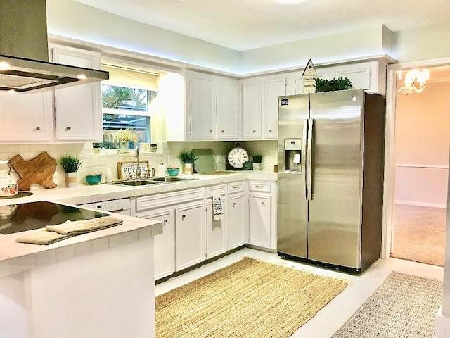 kitchen with extractor fan, sink, white cabinetry, stainless steel fridge, and backsplash