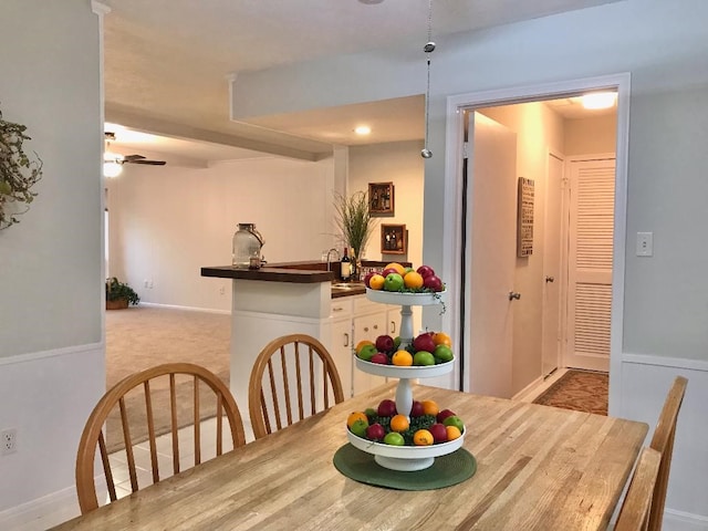 dining space with light carpet and ceiling fan