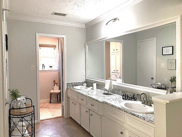 bathroom featuring tile patterned flooring, vanity, a textured ceiling, and crown molding