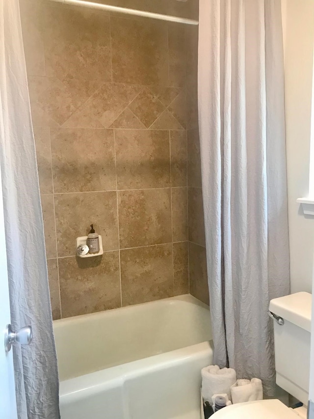 bathroom featuring shower / tub combo and toilet