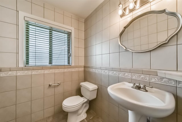 bathroom featuring tile walls, sink, and toilet