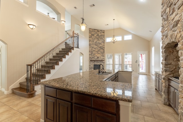 kitchen featuring stone counters, a fireplace, decorative light fixtures, sink, and dark brown cabinets