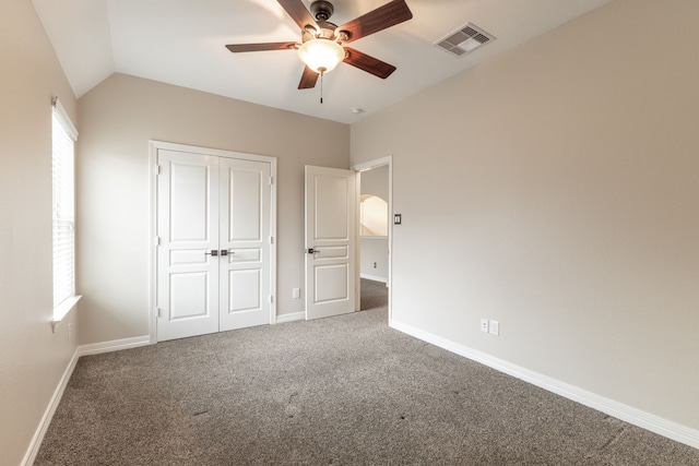 unfurnished bedroom with ceiling fan, a closet, vaulted ceiling, and carpet