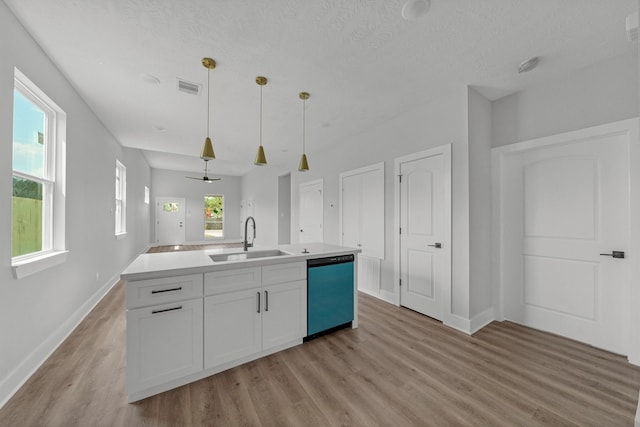 kitchen with decorative light fixtures, dishwasher, an island with sink, sink, and white cabinets