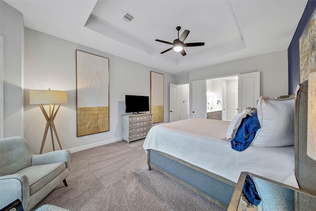 carpeted bedroom featuring ceiling fan, ensuite bath, and a tray ceiling