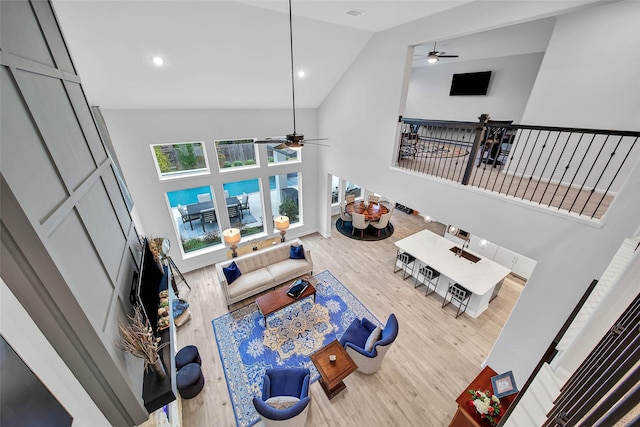 living room featuring high vaulted ceiling, ceiling fan, and light wood-type flooring