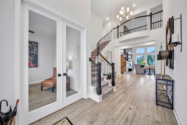 foyer entrance with french doors, an inviting chandelier, hardwood / wood-style floors, and a high ceiling