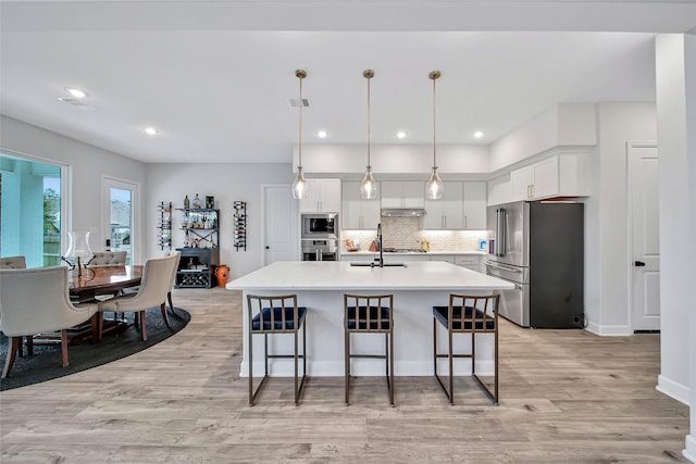 kitchen with hanging light fixtures, an island with sink, white cabinets, and appliances with stainless steel finishes