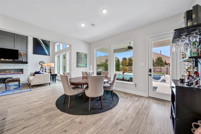 dining area with a fireplace, a healthy amount of sunlight, and light wood-type flooring