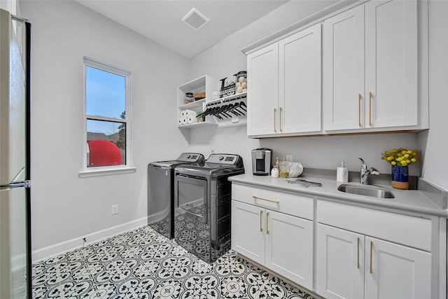 laundry room with cabinets, sink, washing machine and dryer, and light tile patterned floors