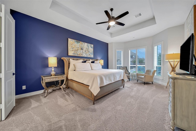 bedroom featuring a raised ceiling, ceiling fan, and carpet flooring