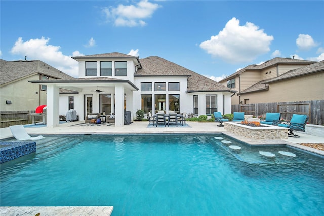 back of house with ceiling fan, a fenced in pool, a patio area, and a fire pit