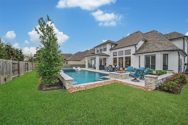 rear view of house featuring a swimming pool with hot tub, a patio, a lawn, and a fire pit