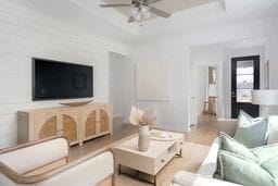 living room featuring ceiling fan, a tray ceiling, and light wood finished floors