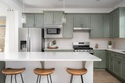 kitchen with light countertops, appliances with stainless steel finishes, and a kitchen bar