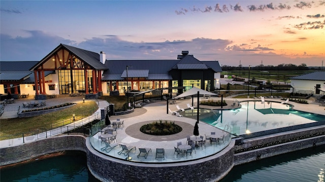 exterior space featuring metal roof, a community pool, a patio area, a standing seam roof, and a chimney