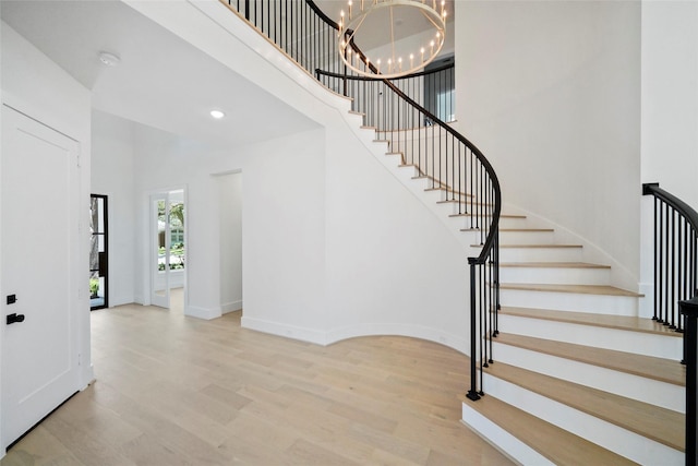 stairs featuring recessed lighting, a high ceiling, an inviting chandelier, wood finished floors, and baseboards