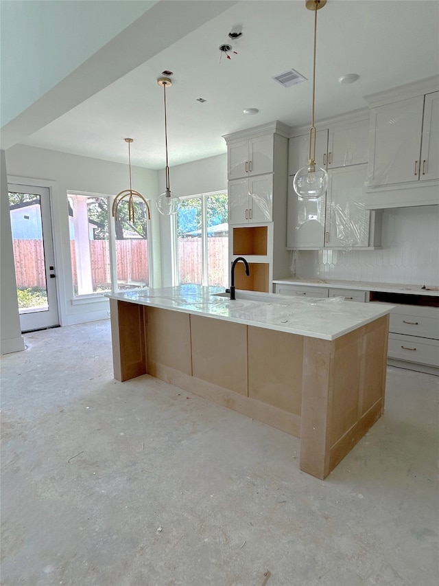 kitchen featuring concrete floors, a sink, a large island with sink, white cabinets, and visible vents