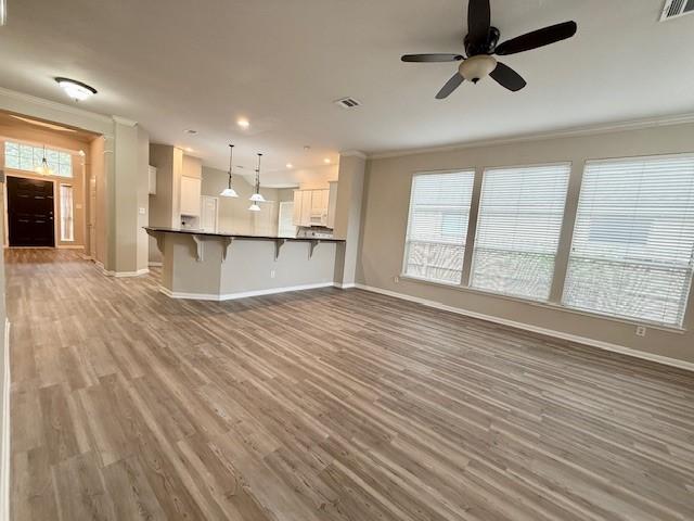 unfurnished living room featuring ornamental molding, light hardwood / wood-style floors, and ceiling fan