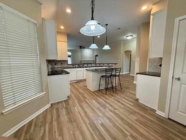 kitchen featuring white cabinetry, light hardwood / wood-style flooring, decorative backsplash, and pendant lighting