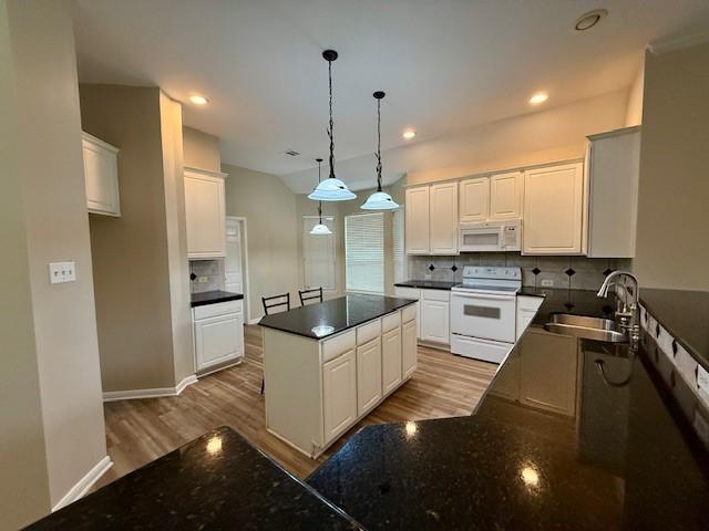 kitchen featuring sink, white cabinetry, hanging light fixtures, white appliances, and decorative backsplash