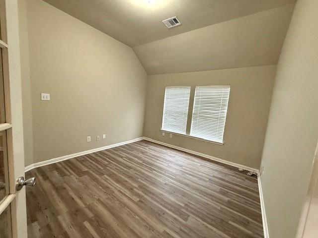 spare room with lofted ceiling and dark wood-type flooring