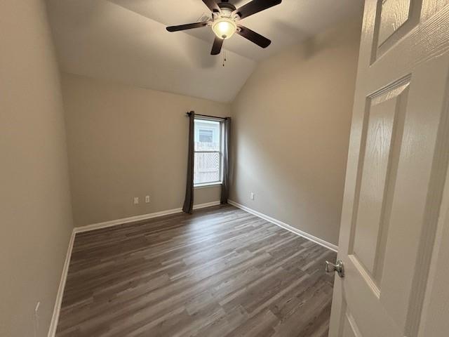 spare room with dark wood-type flooring, ceiling fan, and vaulted ceiling