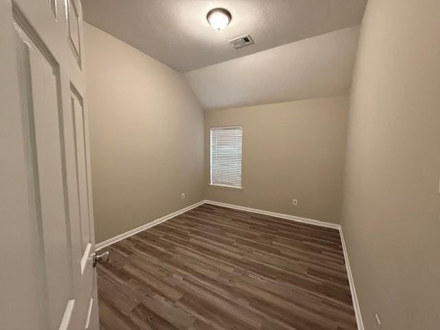 unfurnished room featuring lofted ceiling, a textured ceiling, and dark hardwood / wood-style flooring