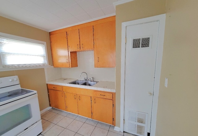 kitchen featuring white electric stove, sink, and light tile patterned floors