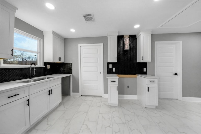 kitchen with white cabinetry, sink, and tasteful backsplash